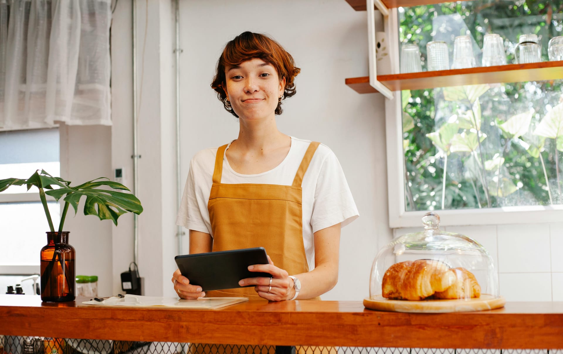 A young person using a tablet behind a cafe counter