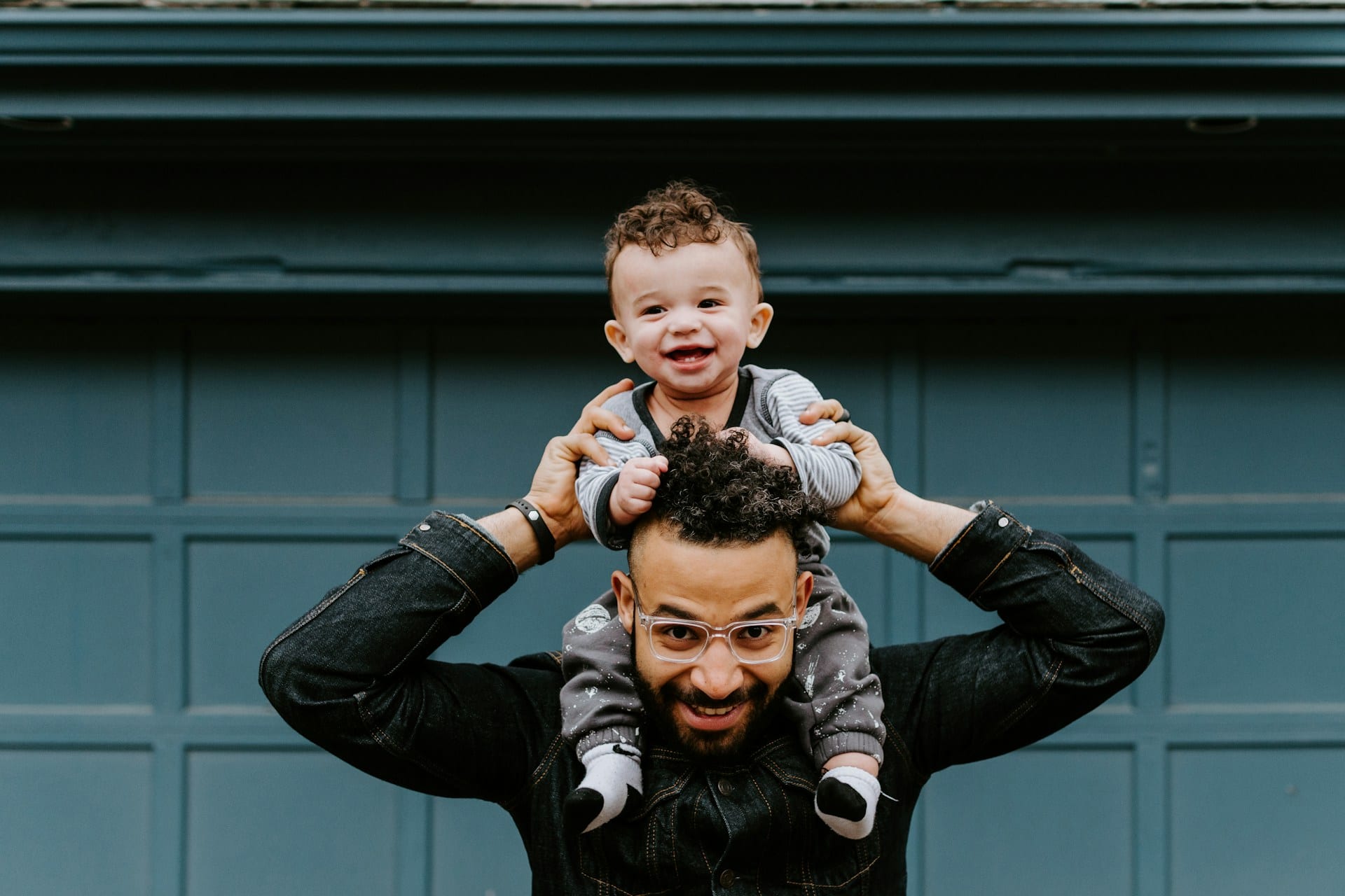 A smiling father carrying his laughing baby on his shoulders